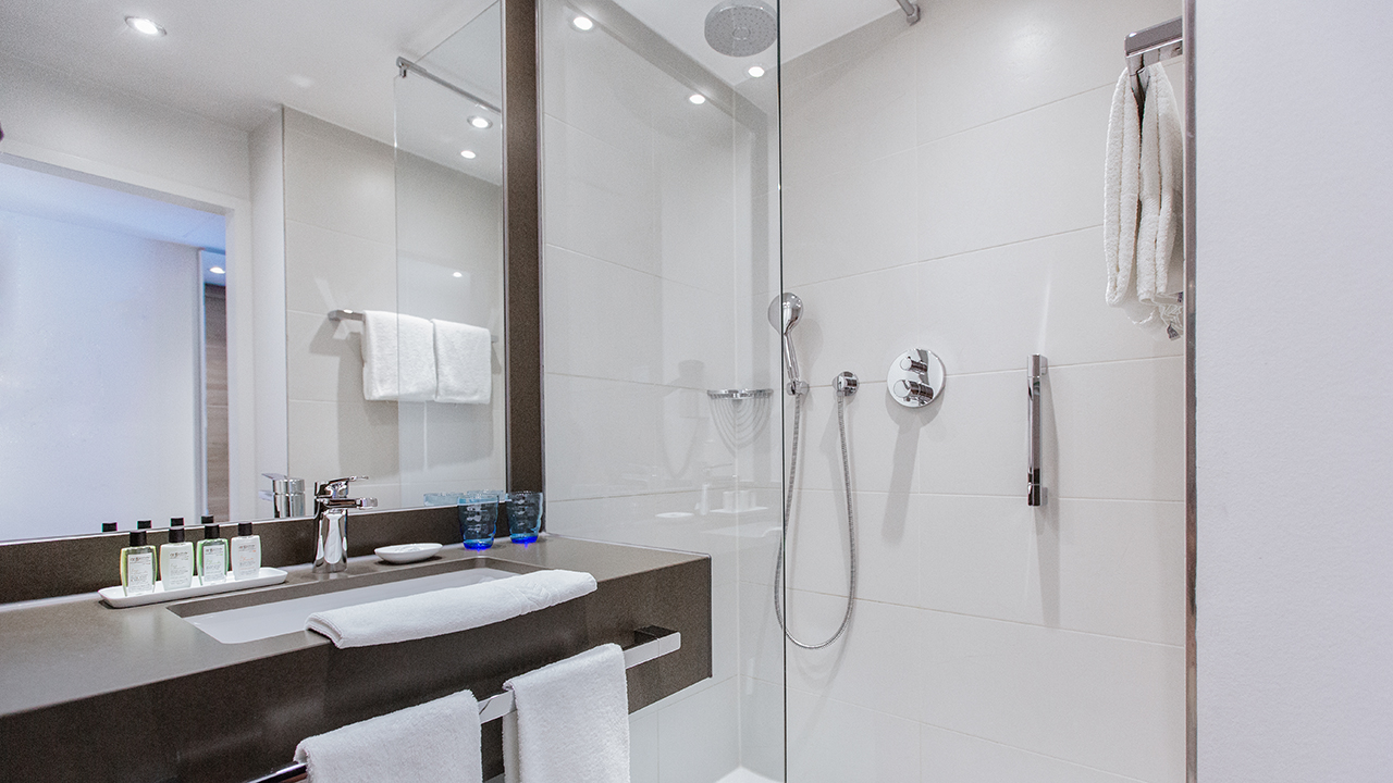 Badezimmer eines Hotelzimmers im The Alex Hotel mit verschiedenen Handseifen, Heizung Waschbecken und Dusche