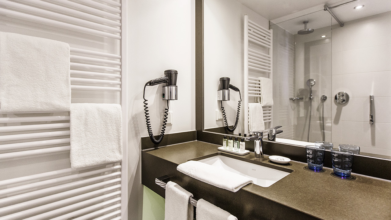 Badezimmer eines Hotelzimmers im The Alex Hotel mit Fön, Heizung und Waschbecken
