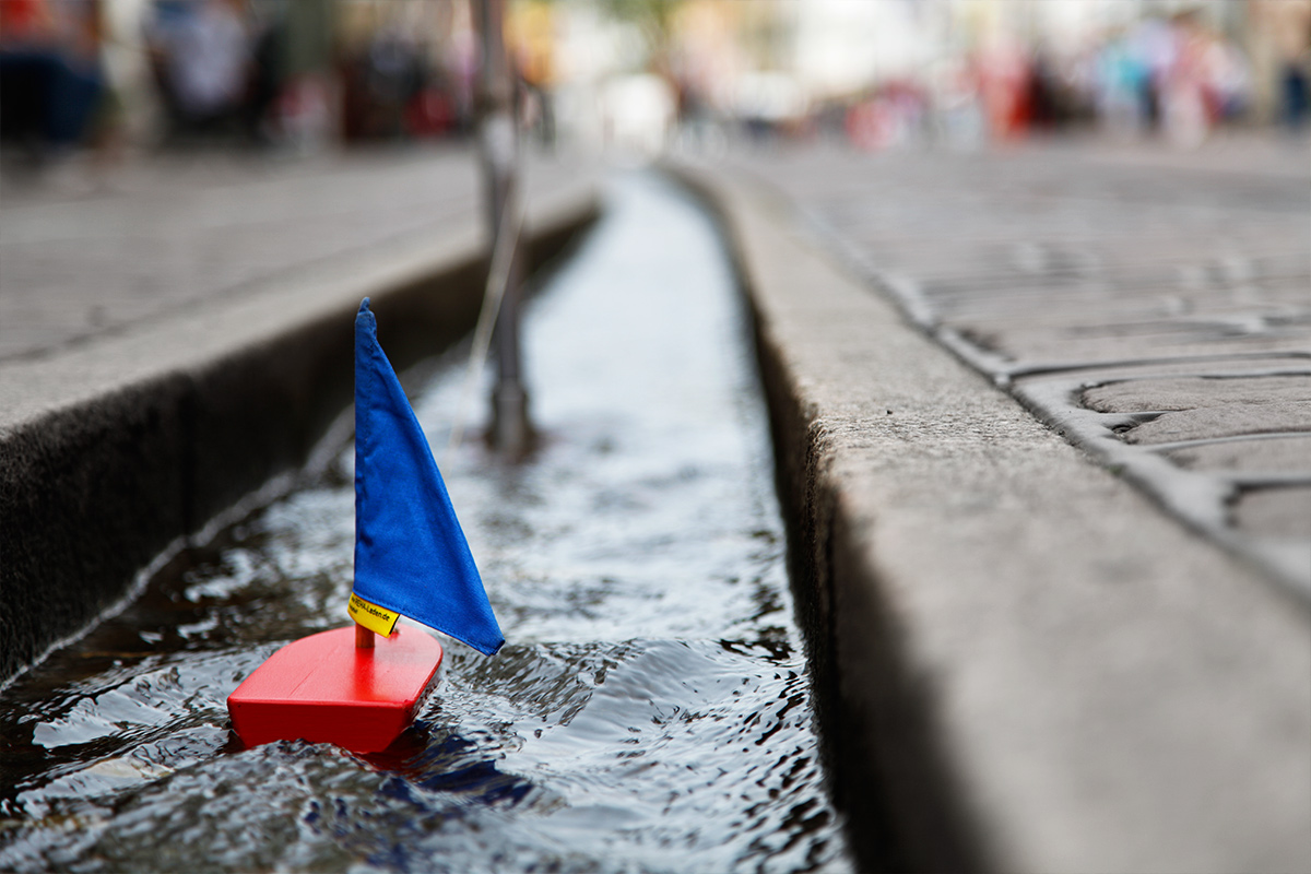 Rotes Spielzeugboot mit blauem Segel im Freiburger Bächle