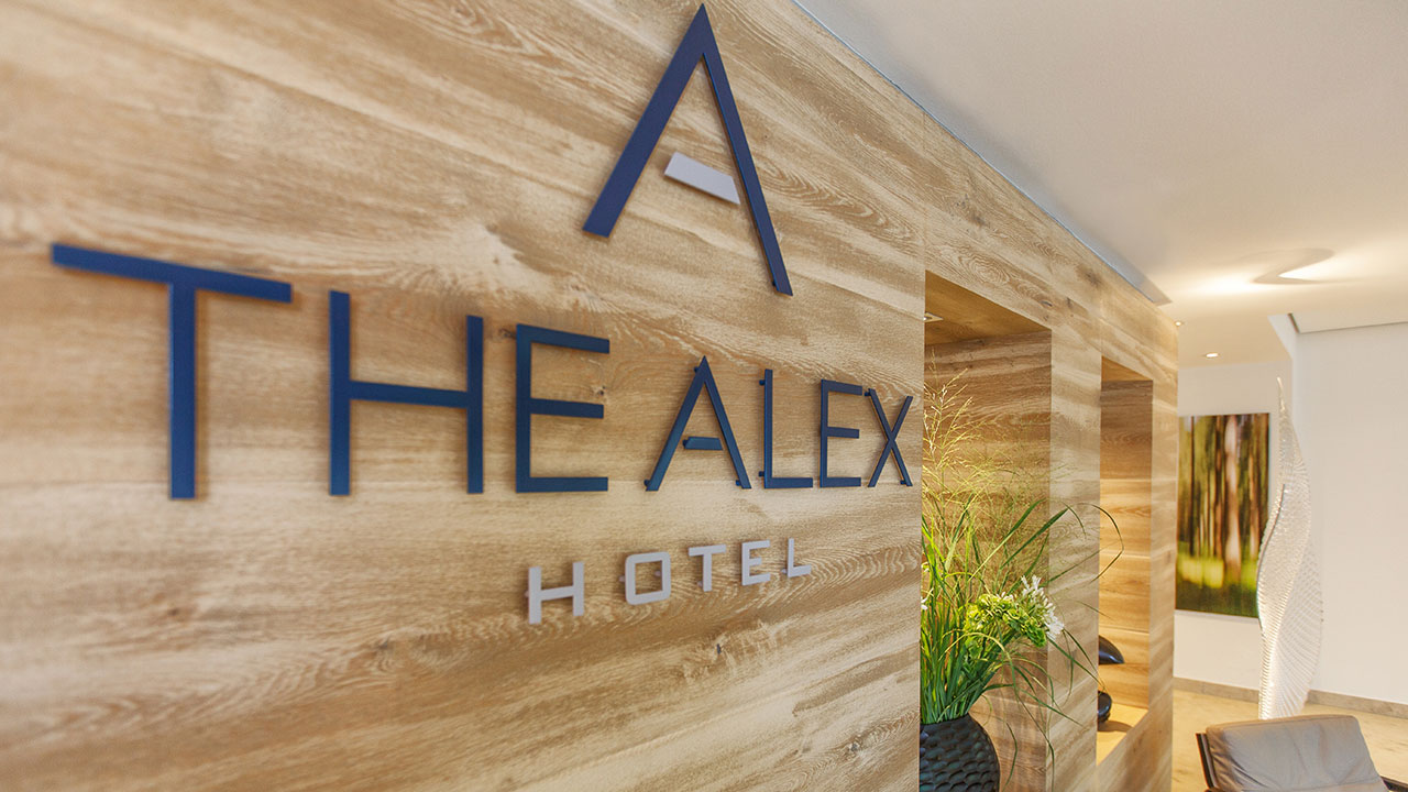 Eingangsbereich von The Alex Hotel mit Logo als Wanddekoration