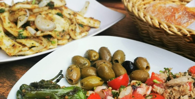 Antipasti-Platten mit Oliven, Tomaten, Paprika und Thunfisch mit Brotkorb